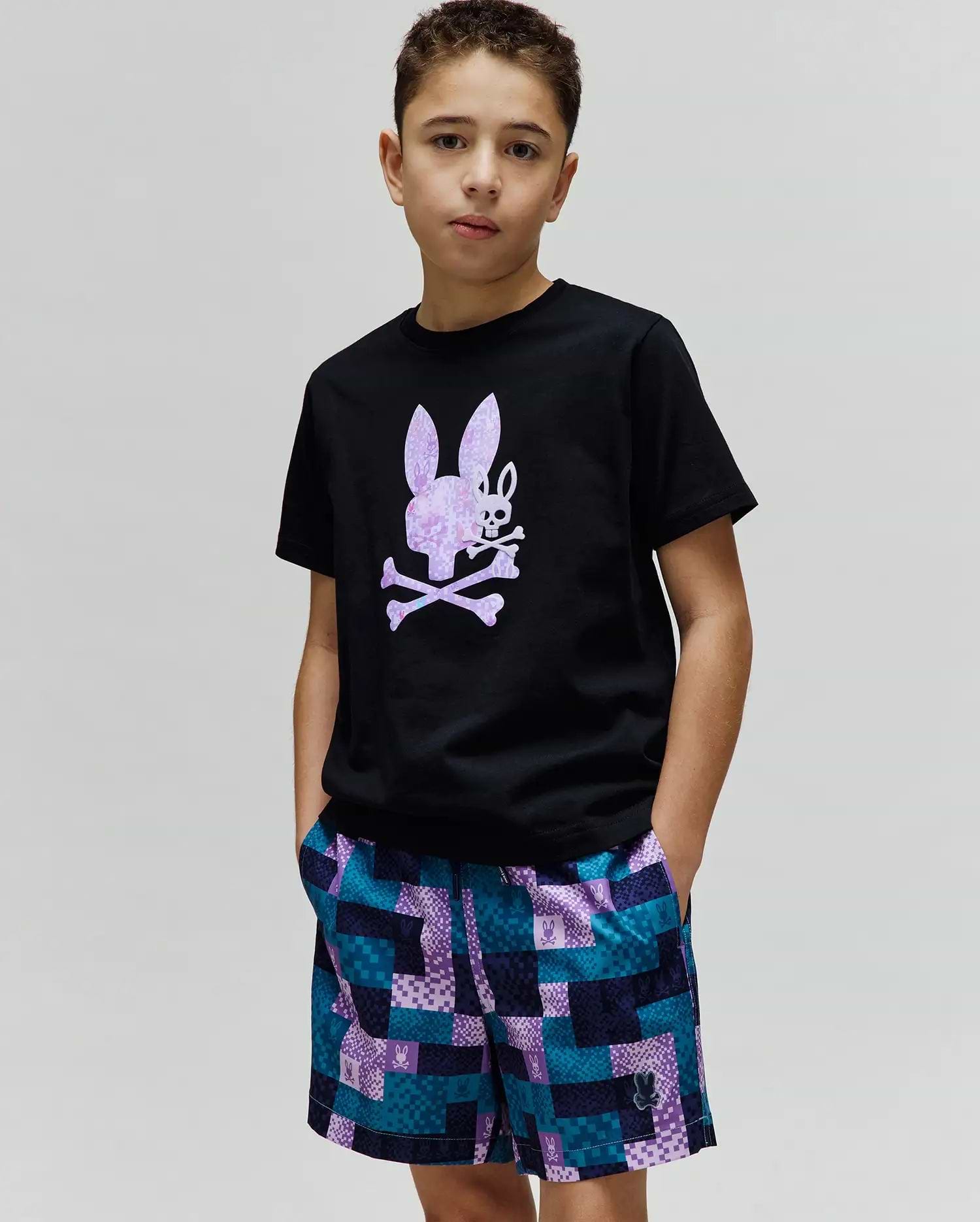 Black Kids Van Graphic Tee, classic fit jersey, with a large pixelated purple and white Psycho Bunny skull chest graphic. Paired with multi-color checkered woven shorts featuring integrated bunny logos. (2)