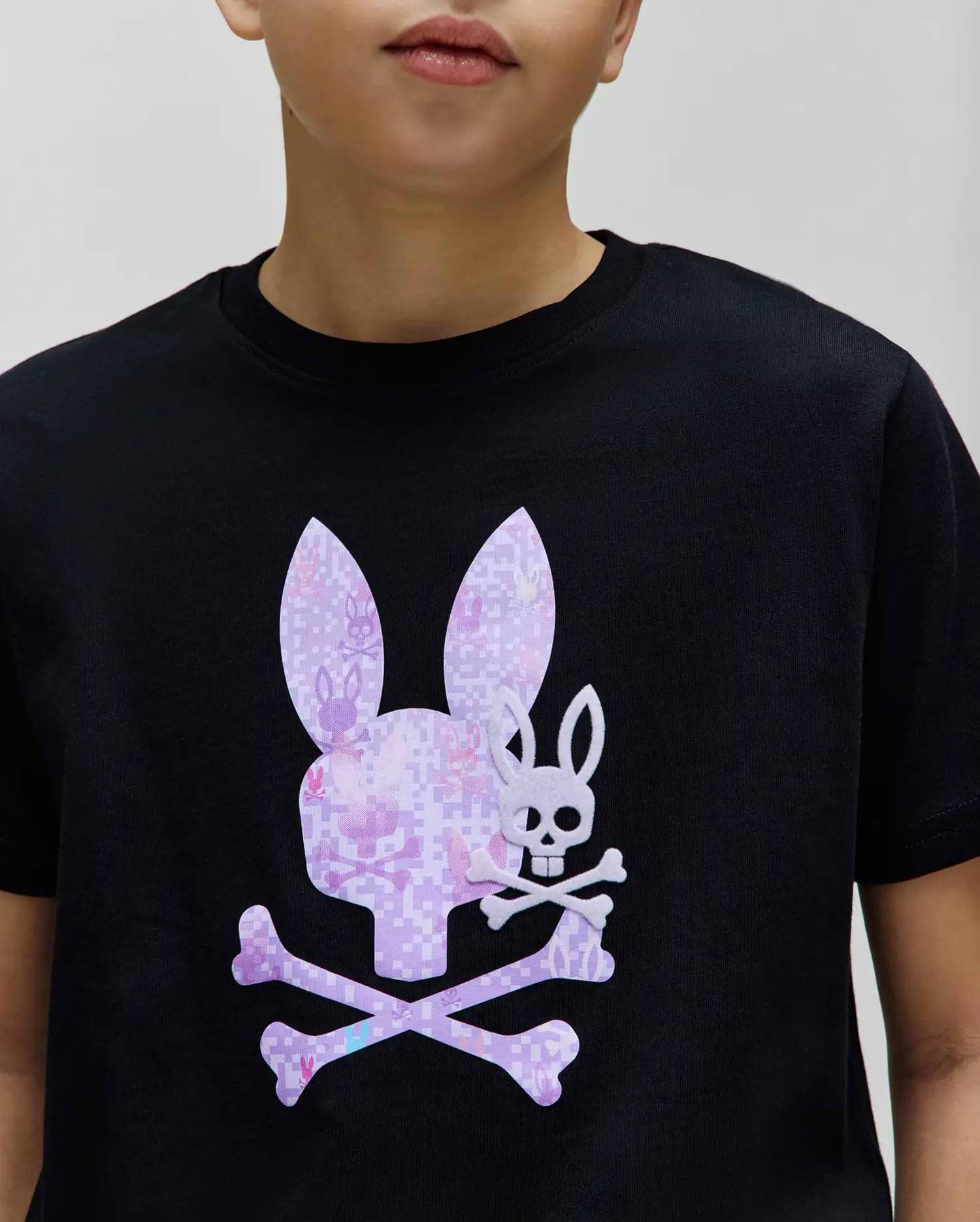 Kids Van Graphic Tee, a classic fit black jersey knit t-shirt featuring a large center chest graphic of a pixelated purple Psycho Bunny skull and crossbones, with a smaller white bunny skull overlay. (3)