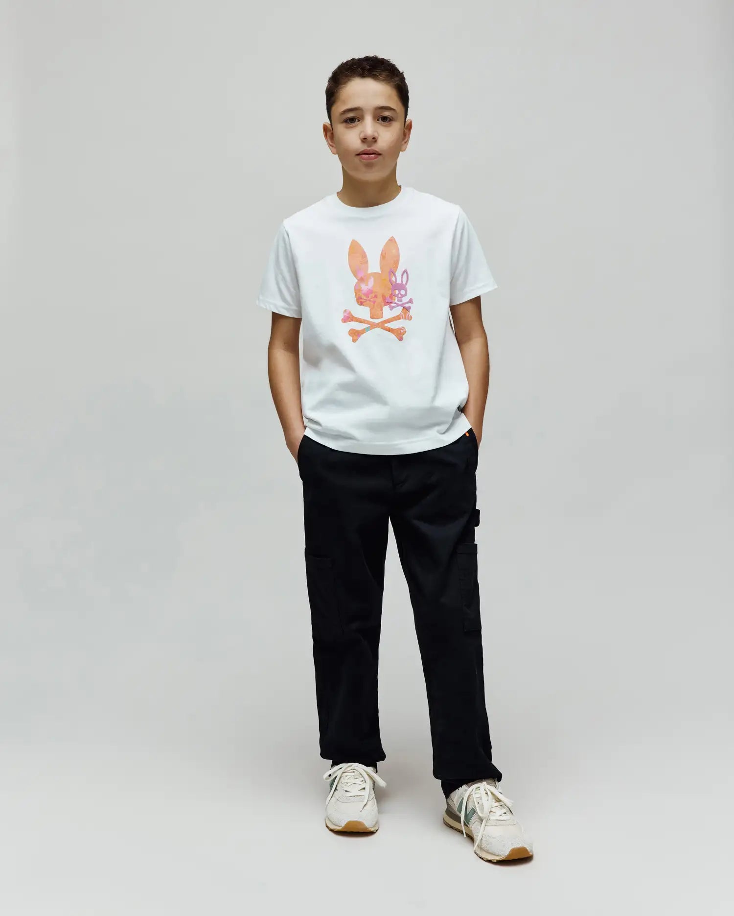White Kids Van Graphic Tee in classic fit, featuring a large orange, pink, and purple watercolor-style Psycho Bunny skull logo with a subtle van pattern and crossed bones on the chest, made from soft jersey fabric. (4)