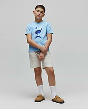 Kids Ara Graphic Tee in light blue jersey knit, featuring a classic fit and a large central chest graphic of the iconic Psycho Bunny skull and crossbones logo in multi-tone blue and white camouflage print.