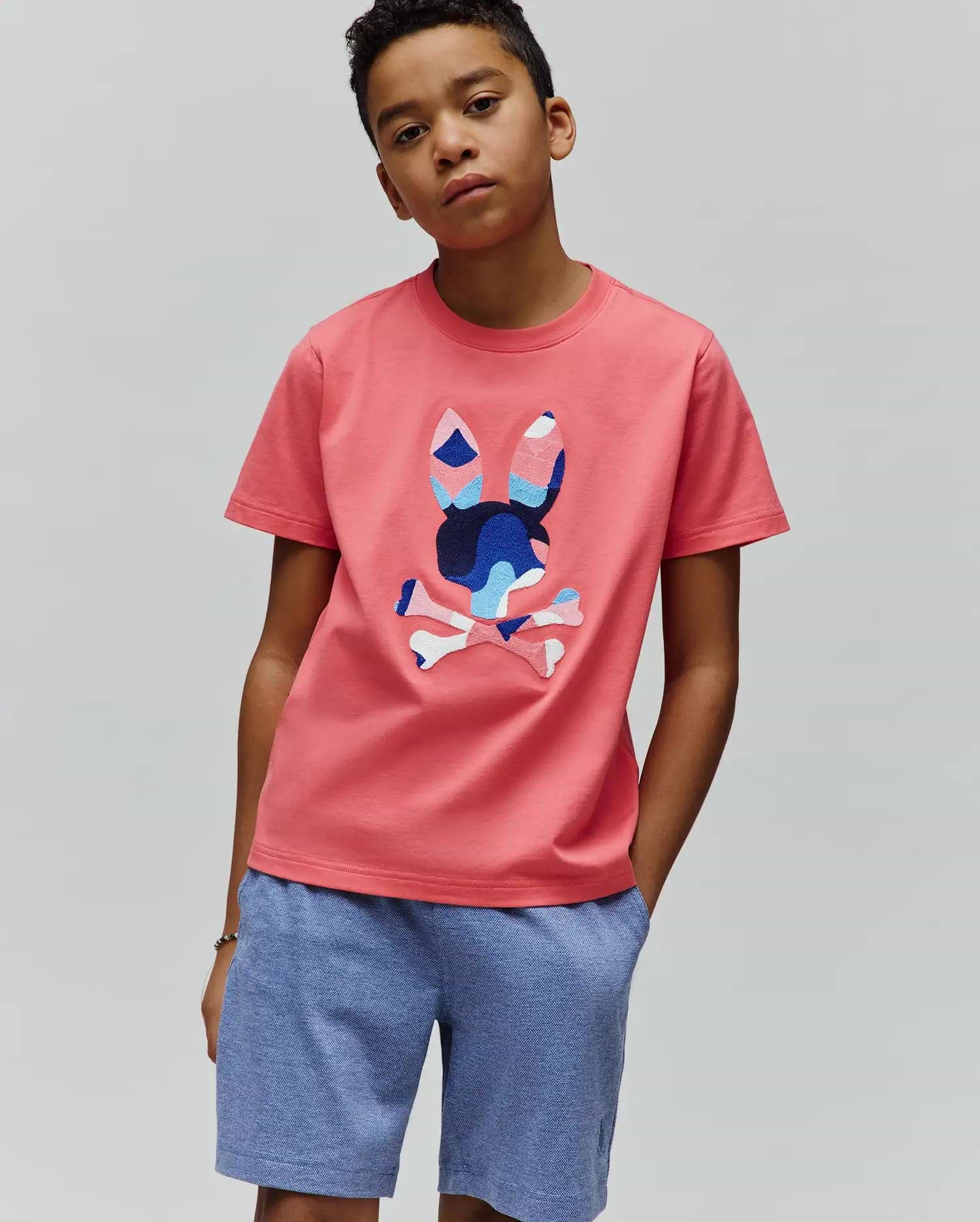 Coral Pink Kids Ara Graphic Tee in classic fit jersey, featuring a large, vibrant blue and white patterned Psycho Bunny skull logo on the center chest.