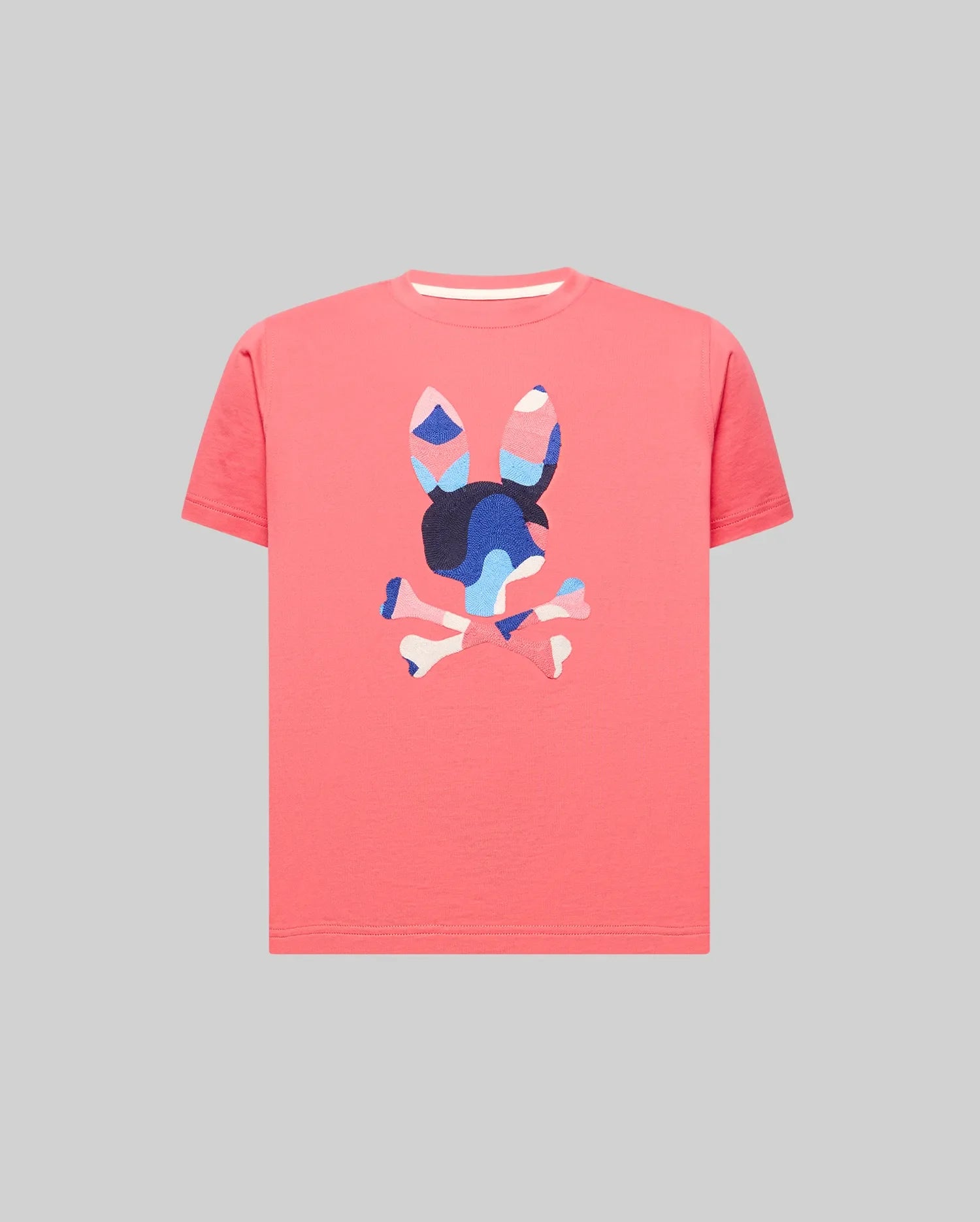 Kids Ara Graphic Tee in vibrant coral, crafted from soft jersey knit with a classic fit. Features a large, textured, multi-color camouflage Psycho Bunny skull logo prominently on the chest.