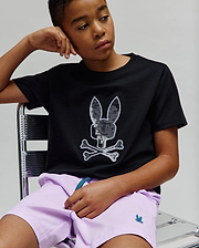 Kids Olivier Graphic Tee, a black classic fit jersey tee with a large sequined silver and white Psycho Bunny skull logo on the chest, paired with lavender woven shorts featuring a small teal embroidered bunny logo. (4)
