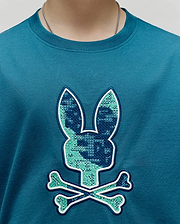 Kids Olivier Graphic Tee, a classic fit teal jersey knit t-shirt with a large central chest embroidered Psycho Bunny skull logo featuring a cross-stitch pattern in dark blue and light green, outlined in white. (3)