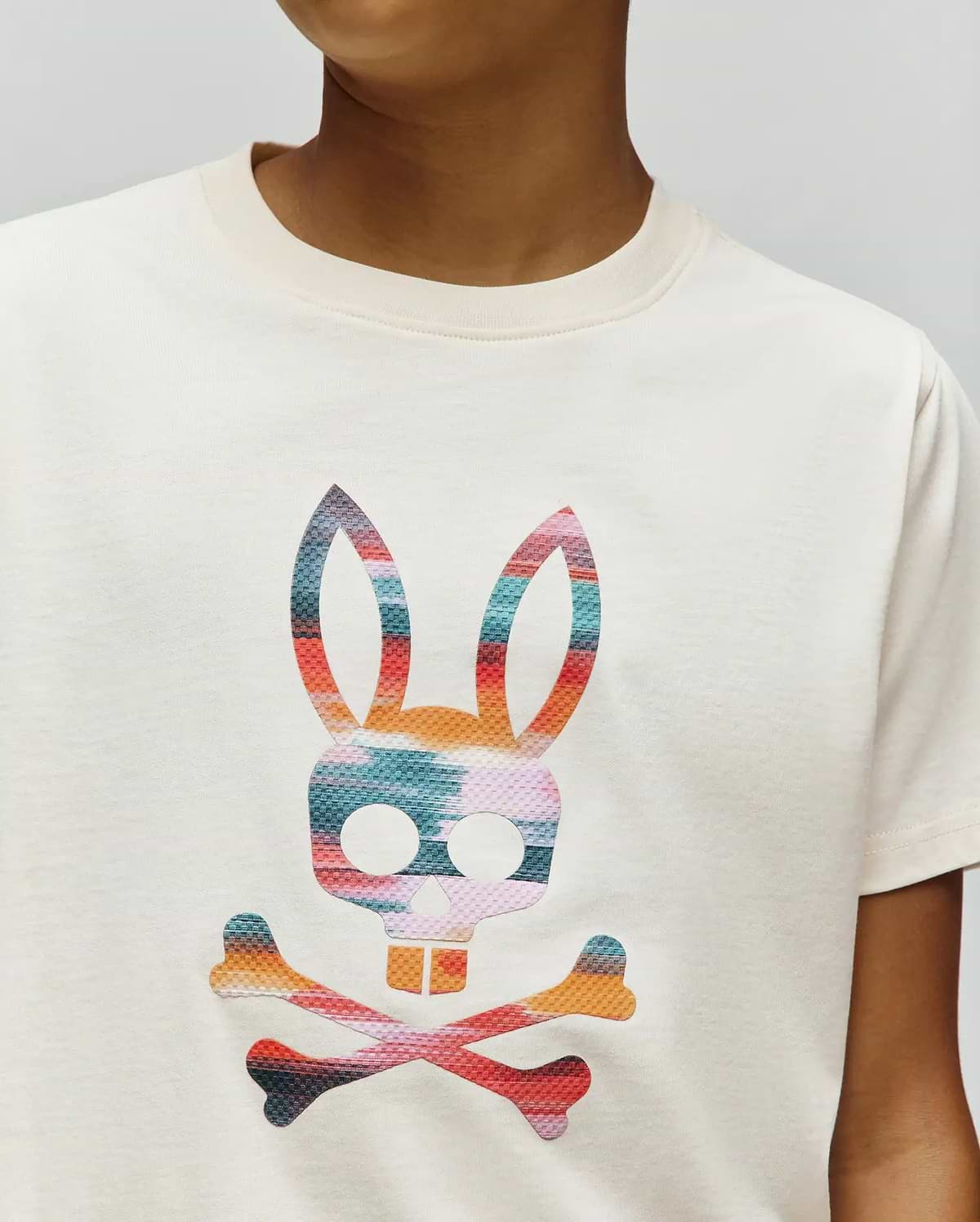 Kids Raphael Graphic Tee in cream jersey knit, featuring a large, vibrant multicolor striped Psycho Bunny skull and crossbones graphic print on the chest.