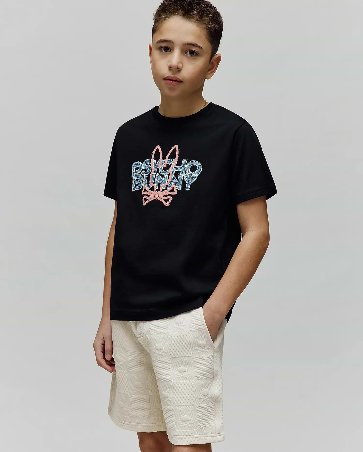 Kids Herman Graphic Tee, black classic fit jersey t-shirt with a large pixelated pink and blue Psycho Bunny logo featuring the iconic bunny skull on the center chest.