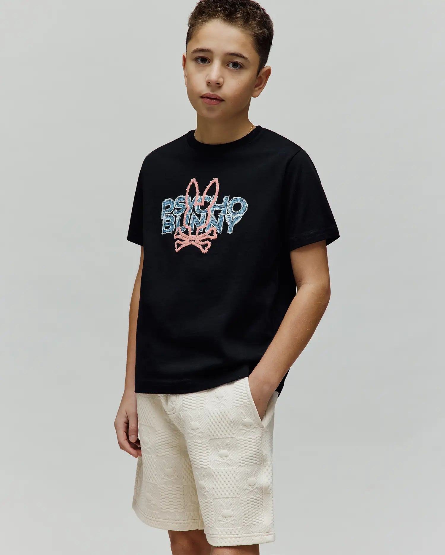 Kids Herman Graphic Tee, black classic fit jersey t-shirt with a large pixelated pink and blue Psycho Bunny logo featuring the iconic bunny skull on the center chest.