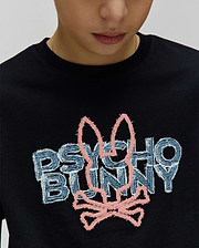 Kids Herman Graphic Tee. Black classic fit jersey t-shirt with a large central embroidered Psycho Bunny logo featuring light blue/white distressed text and a pink textured bunny skull.