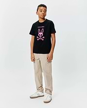 Kids Adler Graphic Tee, a black cotton jersey t-shirt with a large pink Psycho Bunny skull and crossbones logo and text on the chest, styled with beige cargo pants.