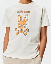 Kids Adler Graphic Tee, a cream classic fit jersey t-shirt with a large central orange and black Psycho Bunny skull and crossbones graphic and PSYCHO BUNNY text.