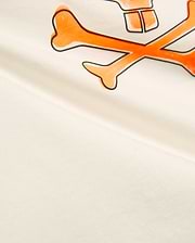 Kids Adler Graphic Tee in soft cream jersey knit, featuring a prominent, large orange and black outlined Psycho Bunny skull and crossbones graphic print on the chest.