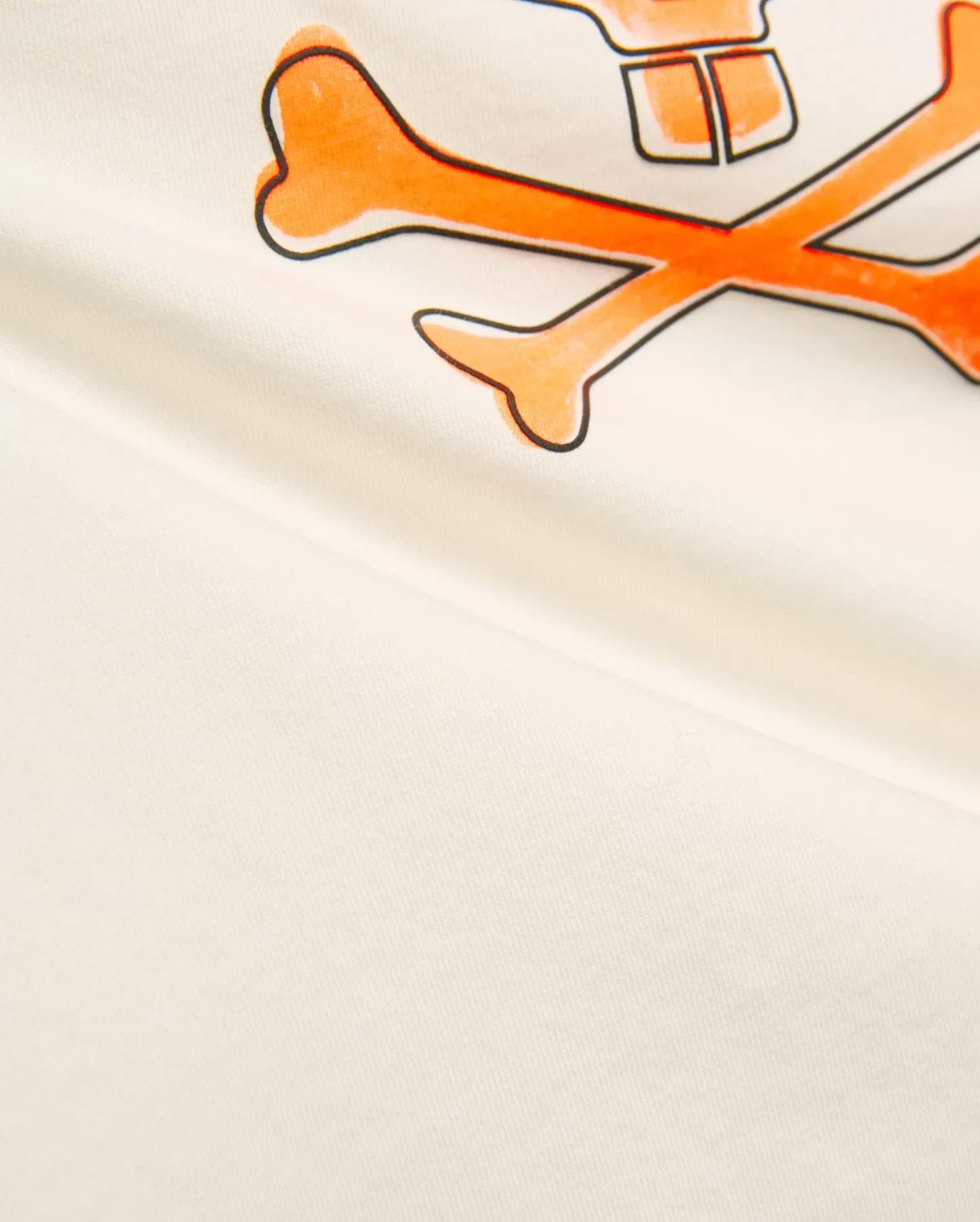 Kids Adler Graphic Tee in soft cream jersey knit, featuring a prominent, large orange and black outlined Psycho Bunny skull and crossbones graphic print on the chest.