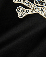 Kids Brad Graphic Tee. Black jersey knit with a large embroidered Psycho Bunny skull logo featuring a white and black tropical pattern of palm trees, bunnies, and skulls, outlined in cream.