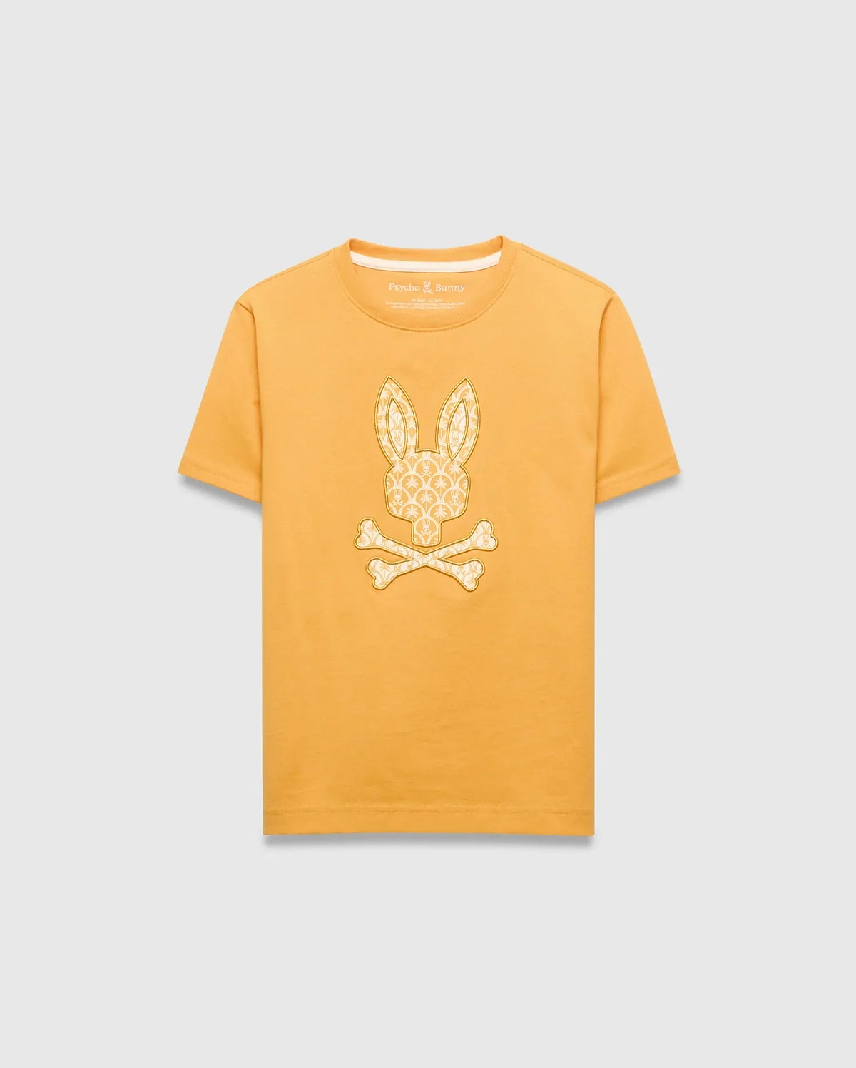 Kids Brad Graphic Tee in golden yellow jersey knit, featuring a large central off-white Psycho Bunny skull logo graphic filled with a subtle repeating bunny pattern, classic fit.