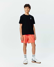 Kids Sunny Chest Graphic Tee, a black jersey t-shirt with a small white embroidered Psycho Bunny skull logo on the left chest, paired with vibrant orange relaxed-fit shorts featuring a tonal bunny logo.