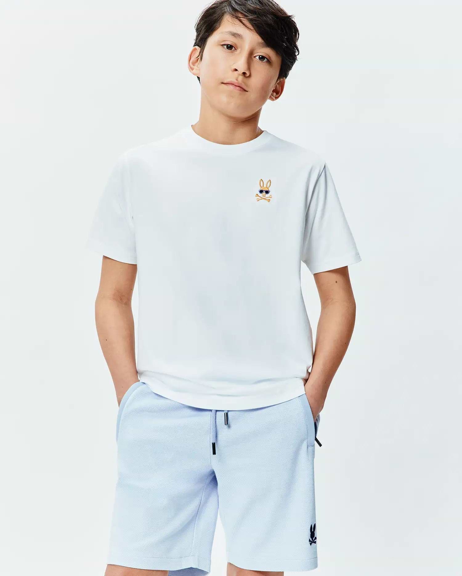 White Kids Sunny Chest Graphic Tee, classic fit jersey, with an embroidered Psycho Bunny sunglasses logo on the chest. Paired with light blue textured shorts featuring a black bunny logo.