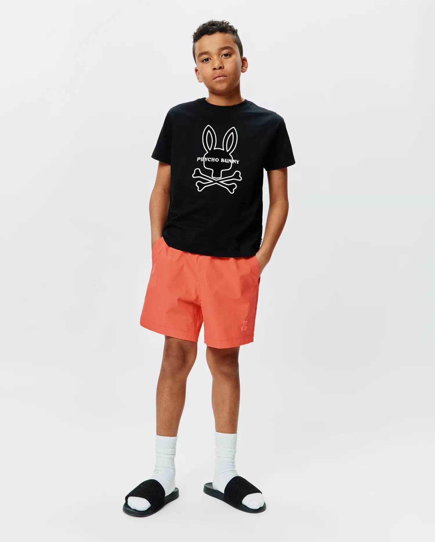 Kids Craig Graphic Tee in black jersey, classic fit, featuring a large white Psycho Bunny skull graphic on the chest, paired with coral woven shorts with a small embroidered Psycho Bunny logo on the left leg. (4)