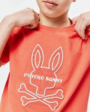 Kids Craig Graphic Tee in coral jersey knit, featuring a large center chest Psycho Bunny skull logo with white outline and textured coral fill, plus white PSYCHO BUNNY text.
