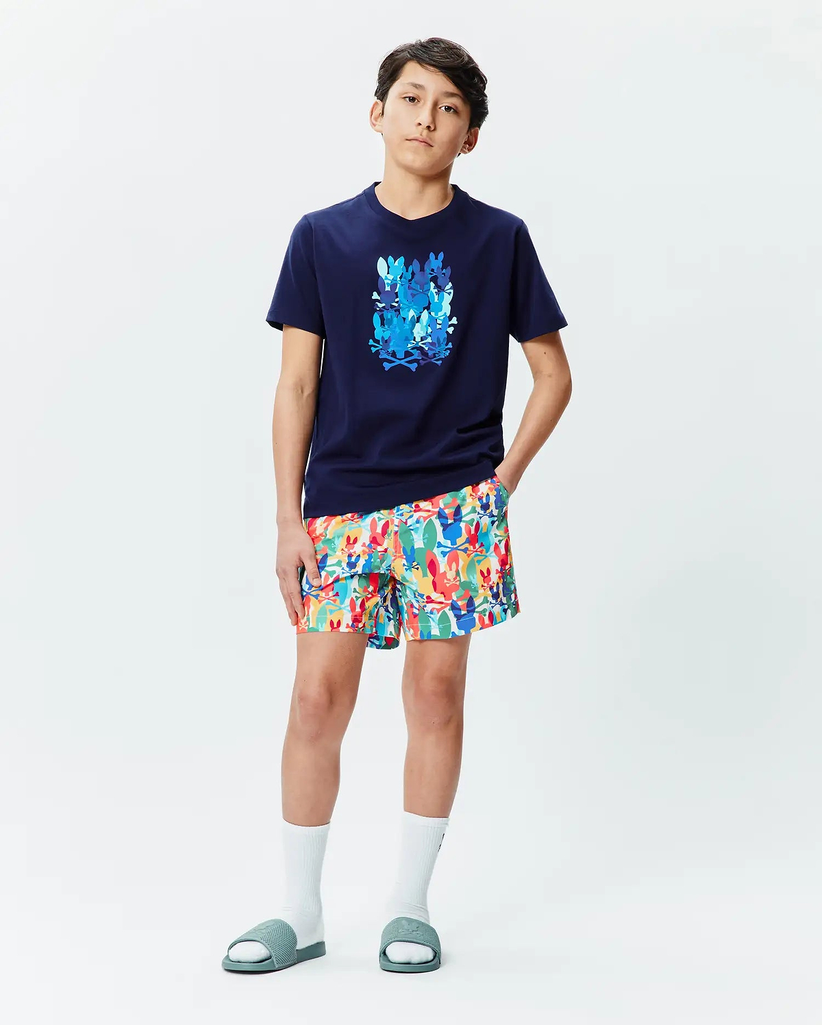 Kids Tanner Graphic Tee: Navy blue classic fit jersey t-shirt with a large blue Psycho Bunny skull graphic on the chest, paired with multi-color allover bunny skull print shorts.
