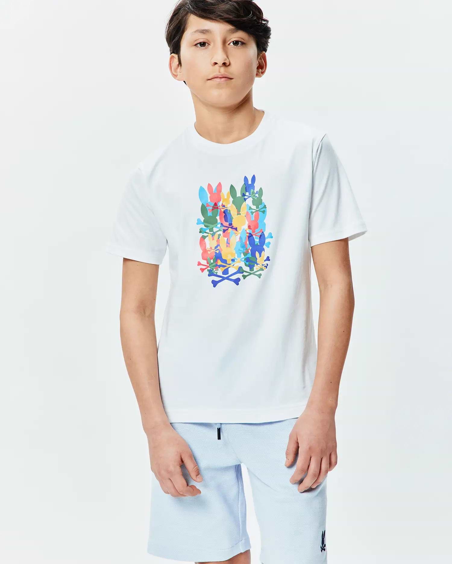 Kids Tanner Graphic Tee, a classic fit white jersey t-shirt featuring a large, vibrant central graphic of stacked, multicolored Psycho Bunny skull and crossbones logos in blue, green, yellow, pink, and orange.