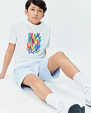White Kids Tanner Graphic Tee with a large, vibrant stacked Psycho Bunny skull and crossbones print on the chest, paired with light blue textured pique shorts. Classic fit.
