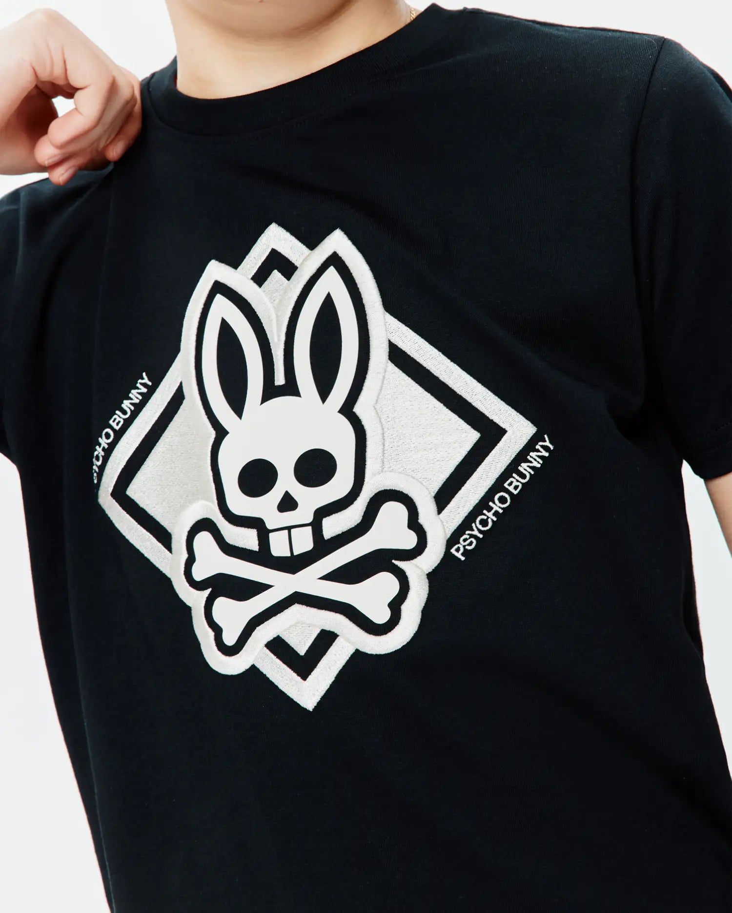 Black classic fit jersey Kids Tobias Graphic Tee with a large, central white embroidered Psycho Bunny skull and crossbones logo inside a diamond, featuring Psycho Bunny text.