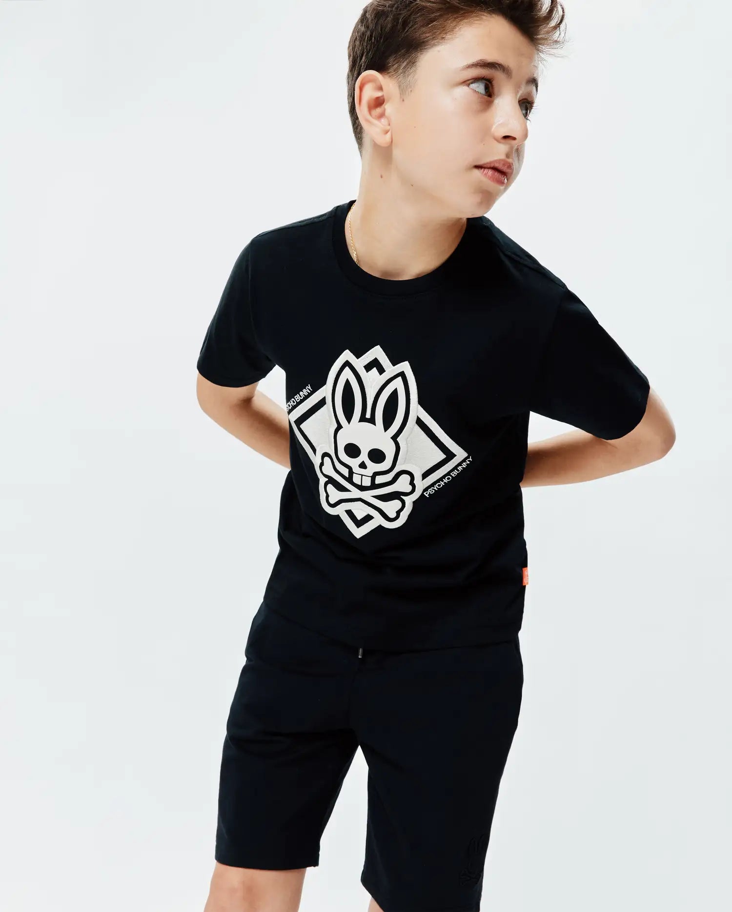 Kids Tobias Graphic Tee. Black cotton jersey classic fit tee with large white central Psycho Bunny skull logo graphic in a diamond, featuring PSYCHO BUNNY text and a small orange side tag.