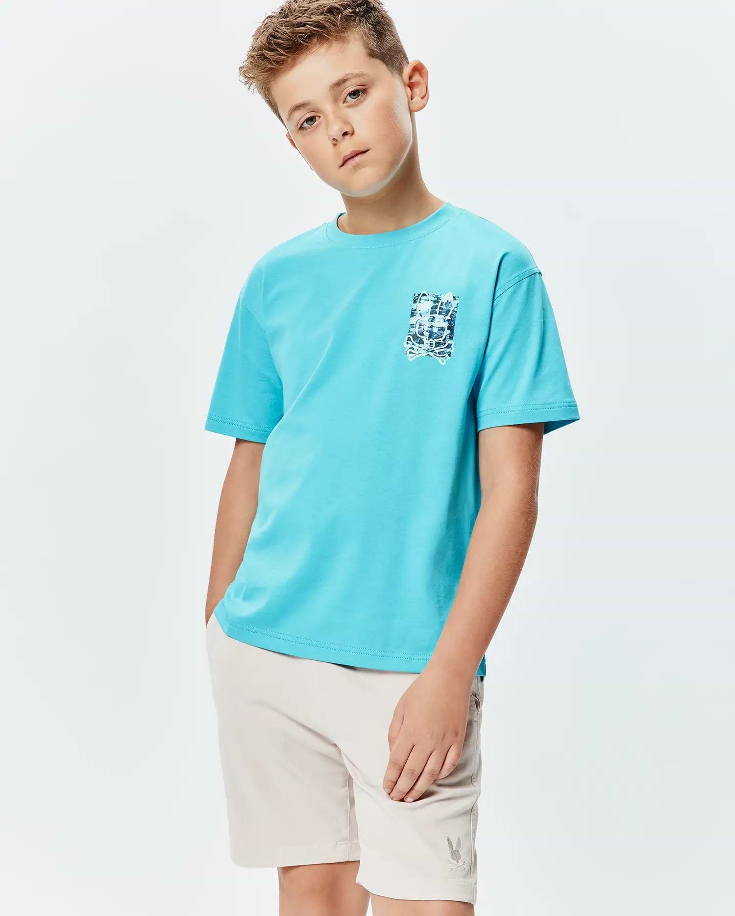 Kids Isaac Relaxed Fit Tee, an aqua blue jersey t-shirt with a relaxed fit and a small, distressed blue and white Psycho Bunny skull graphic on the left chest.