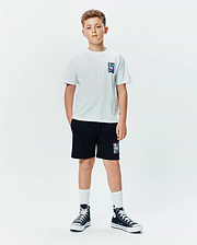 Kids Isaac Relaxed Fit Tee in white jersey with a small, colorful abstract bunny skull logo on the left chest, paired with black french terry shorts featuring a larger matching logo.
