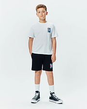 Kids Isaac Relaxed Fit Tee in white jersey with a small, colorful abstract bunny skull logo on the left chest, paired with black french terry shorts featuring a larger matching logo.