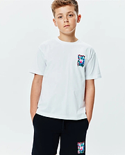 Kids Isaac Relaxed Fit Tee, a white jersey t-shirt featuring a vibrant, abstract Psycho Bunny skull logo graphic on the left chest. Black shorts with a matching colorful bunny skull logo on the left thigh complete the look.