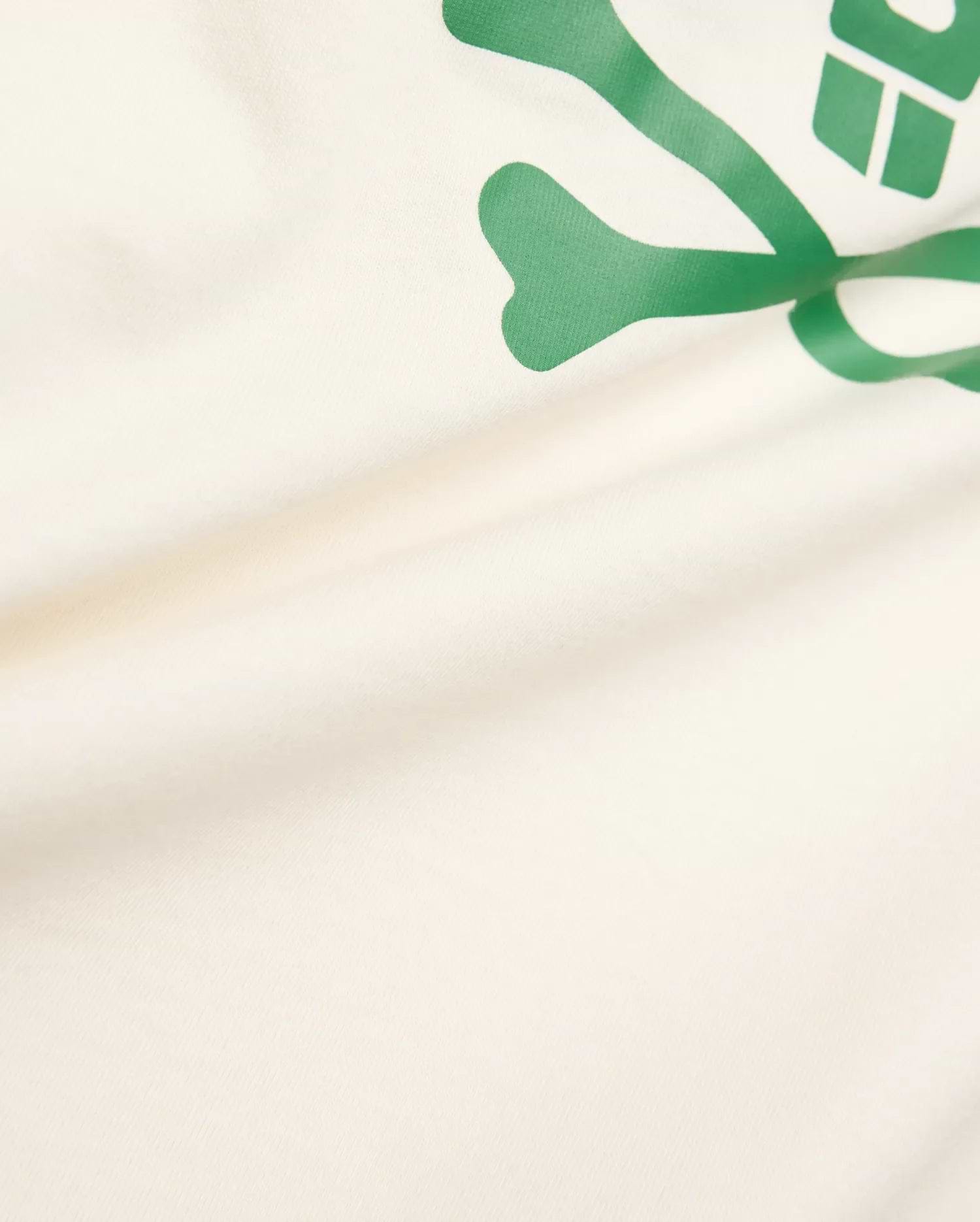 Kids Sunny Graphic Tee crafted from soft cream jersey knit, showcasing a prominent, vibrant green Psycho Bunny skull and crossbones graphic print for a comfortable classic fit.