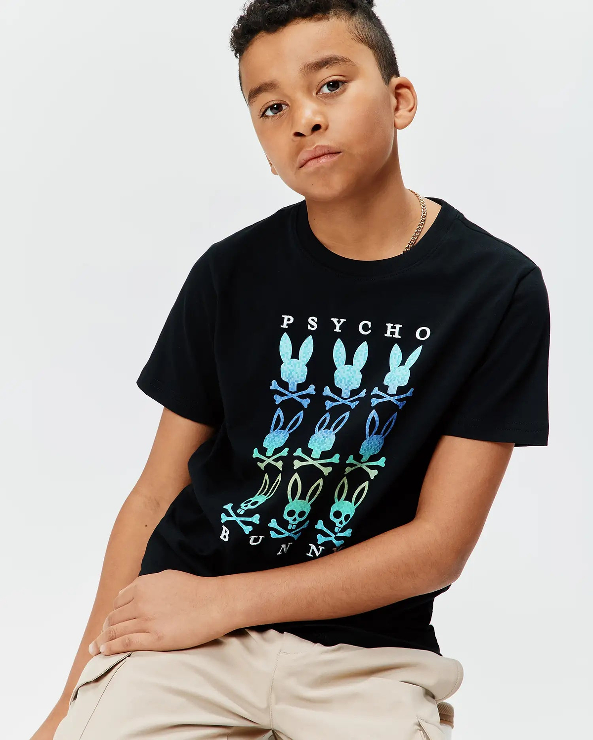 Kids Colt Graphic Tee, black jersey with a large chest print featuring a grid of gradient blue and green Psycho Bunny skull logos and white PSYCHO BUNNY text, classic fit.