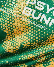 Kids Joshua Soccer Tee in vibrant green performance jersey, featuring bold yellow geometric hexagonal and triangular patterns, with large white PSYCHO BUNNY text and a PERFORMANCE THAT NEVER SLEEPS tagline.