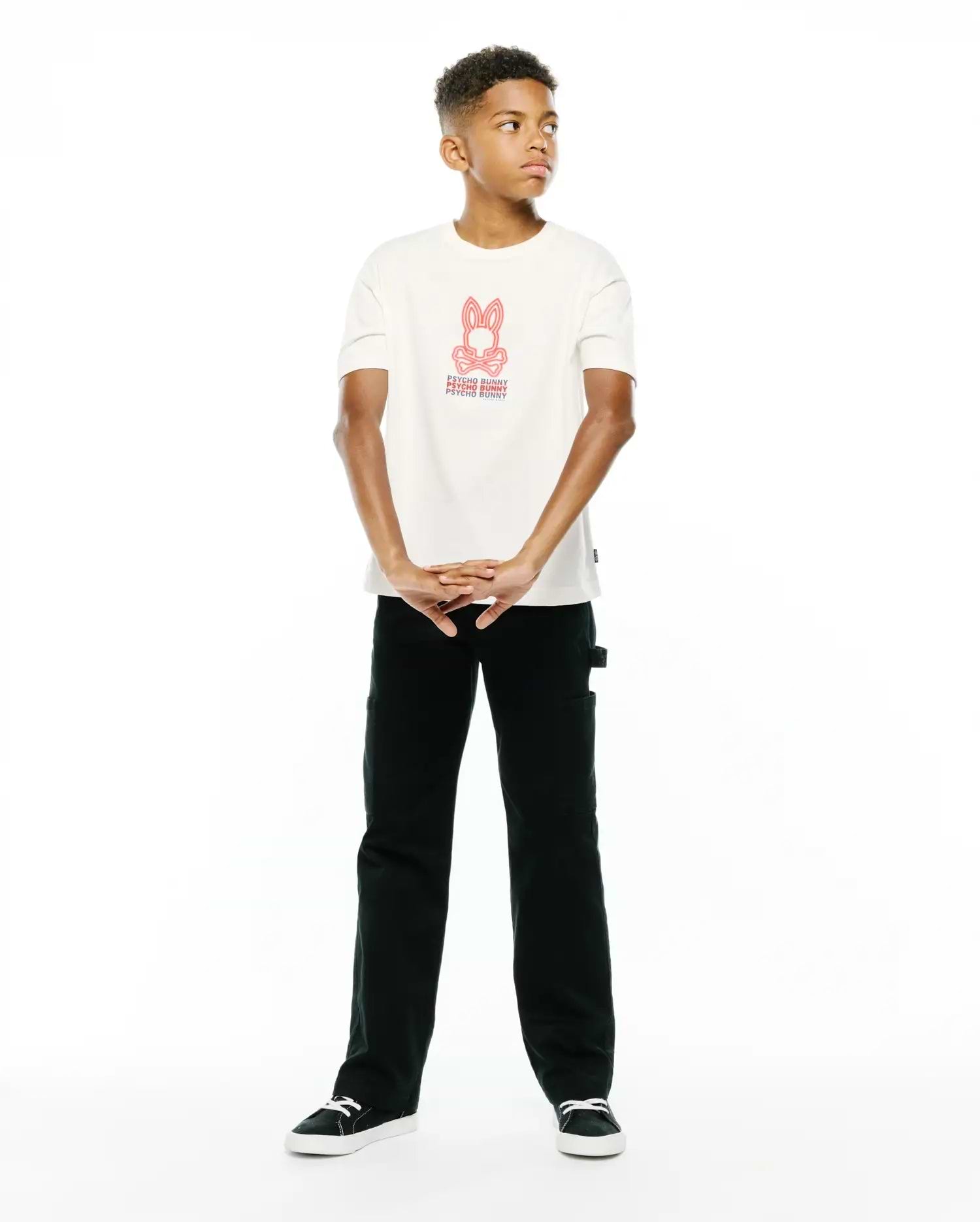 Premium cream jersey Kids Alex Relaxed Back Graphic Tee, featuring a bold red iconic Psycho Bunny skull logo and repeated text graphic on the center chest for refined streetwear style.