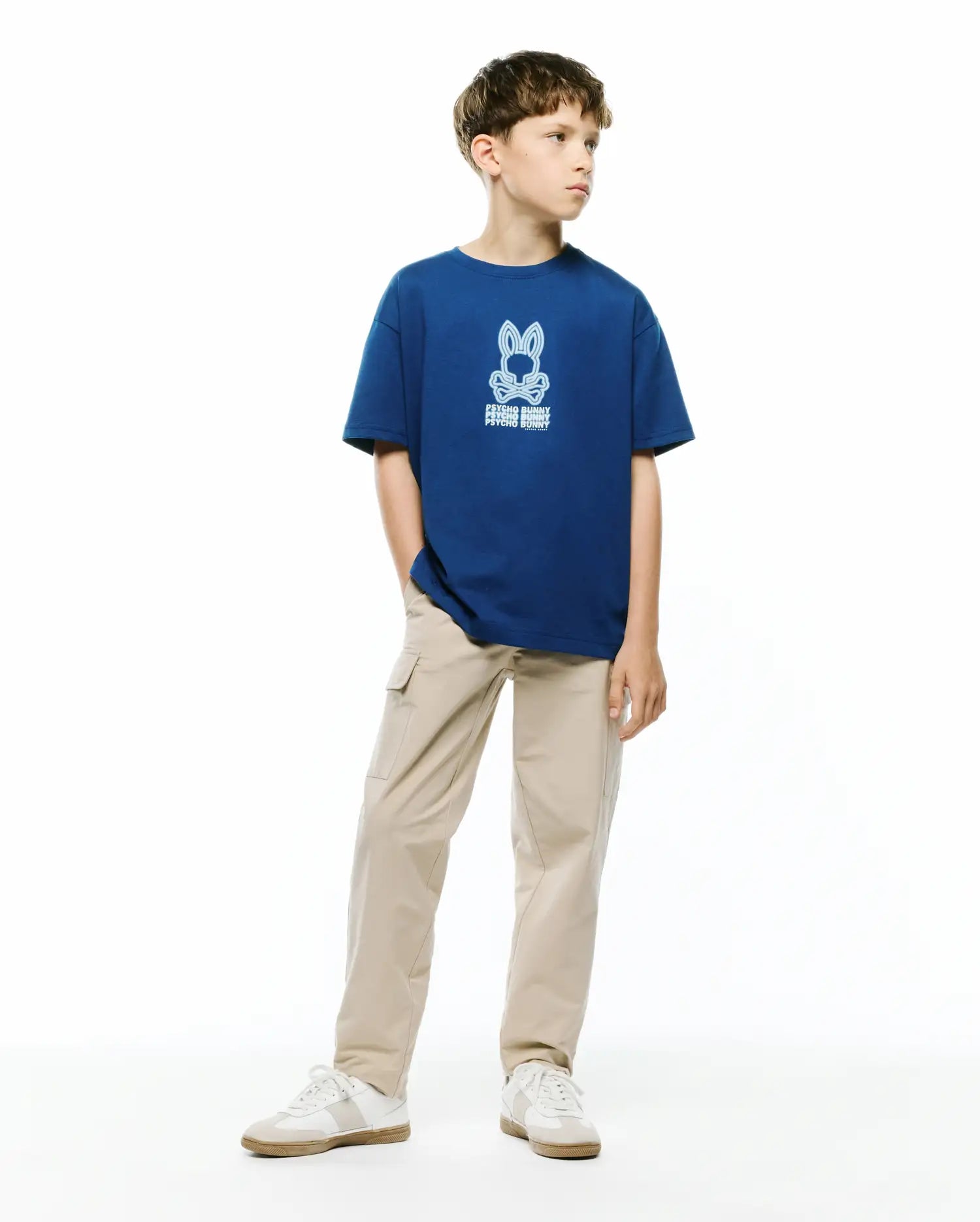 Kids Alex Relaxed Back Graphic Tee, a royal blue jersey t-shirt with a large light blue Psycho Bunny skull and crossbones logo graphic on the chest, featuring repeated brand text, in a relaxed fit.