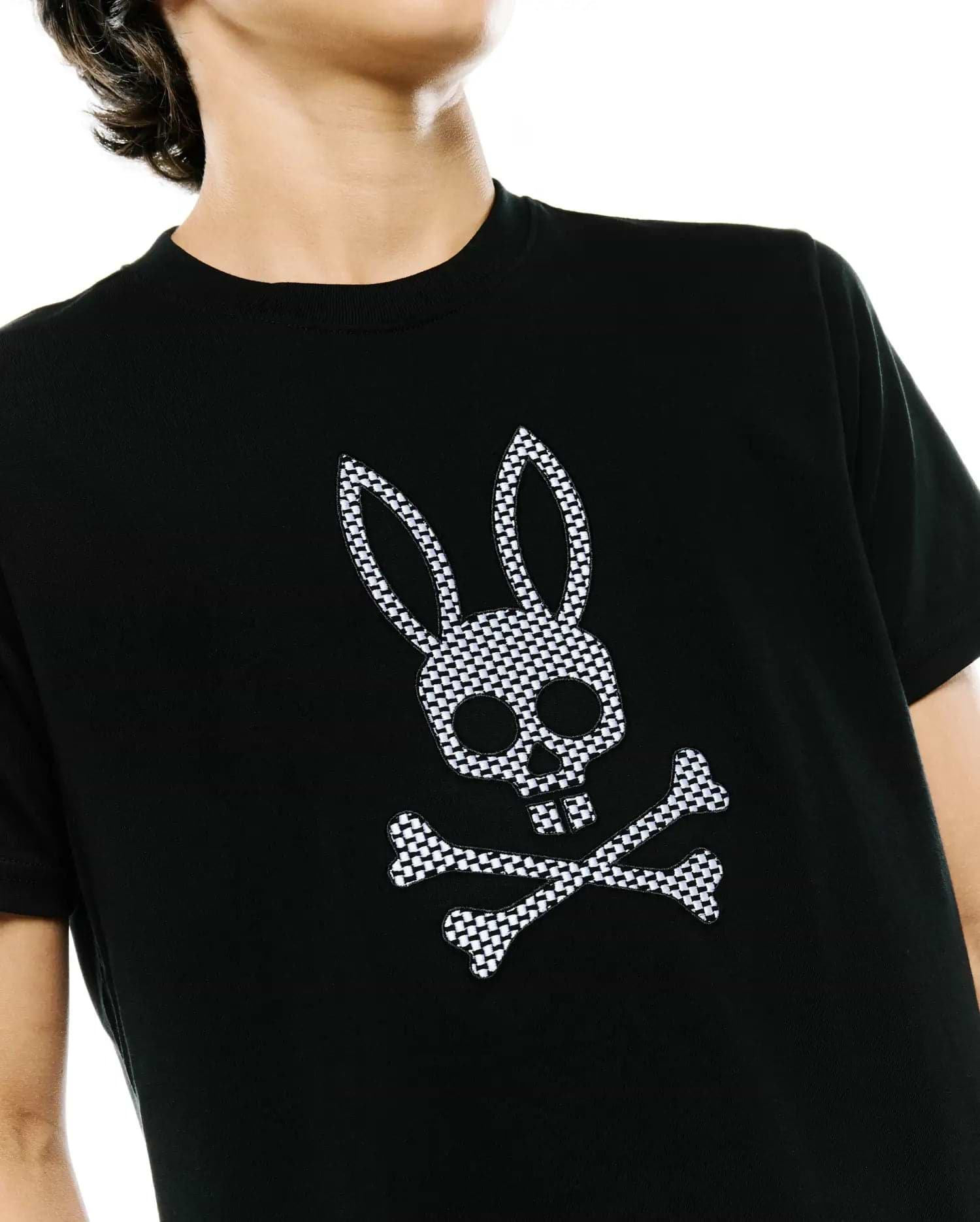 Psycho Bunny Kids Stan Graphic Tee in black, a classic fit jersey t-shirt with a prominent, embroidered black and white checkered bunny skull and crossbones logo on the chest.