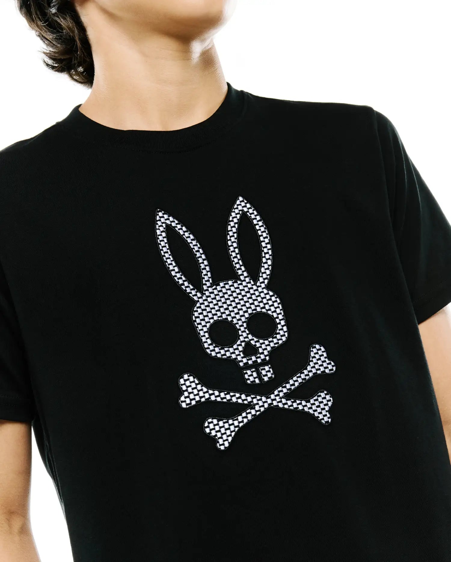 Psycho Bunny Kids Stan Graphic Tee in black, a classic fit jersey t-shirt with a prominent, embroidered black and white checkered bunny skull and crossbones logo on the chest.