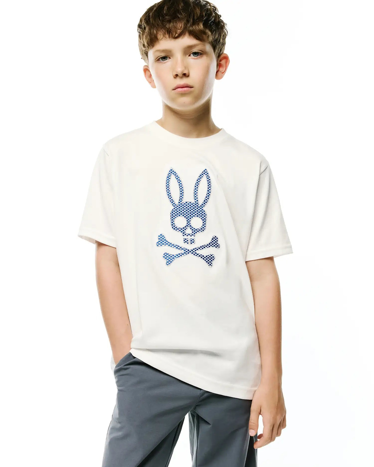 Kids Stan Graphic Tee, a cream classic fit soft jersey knit t-shirt featuring a large, centered blue checkered Psycho Bunny skull and crossbones graphic.