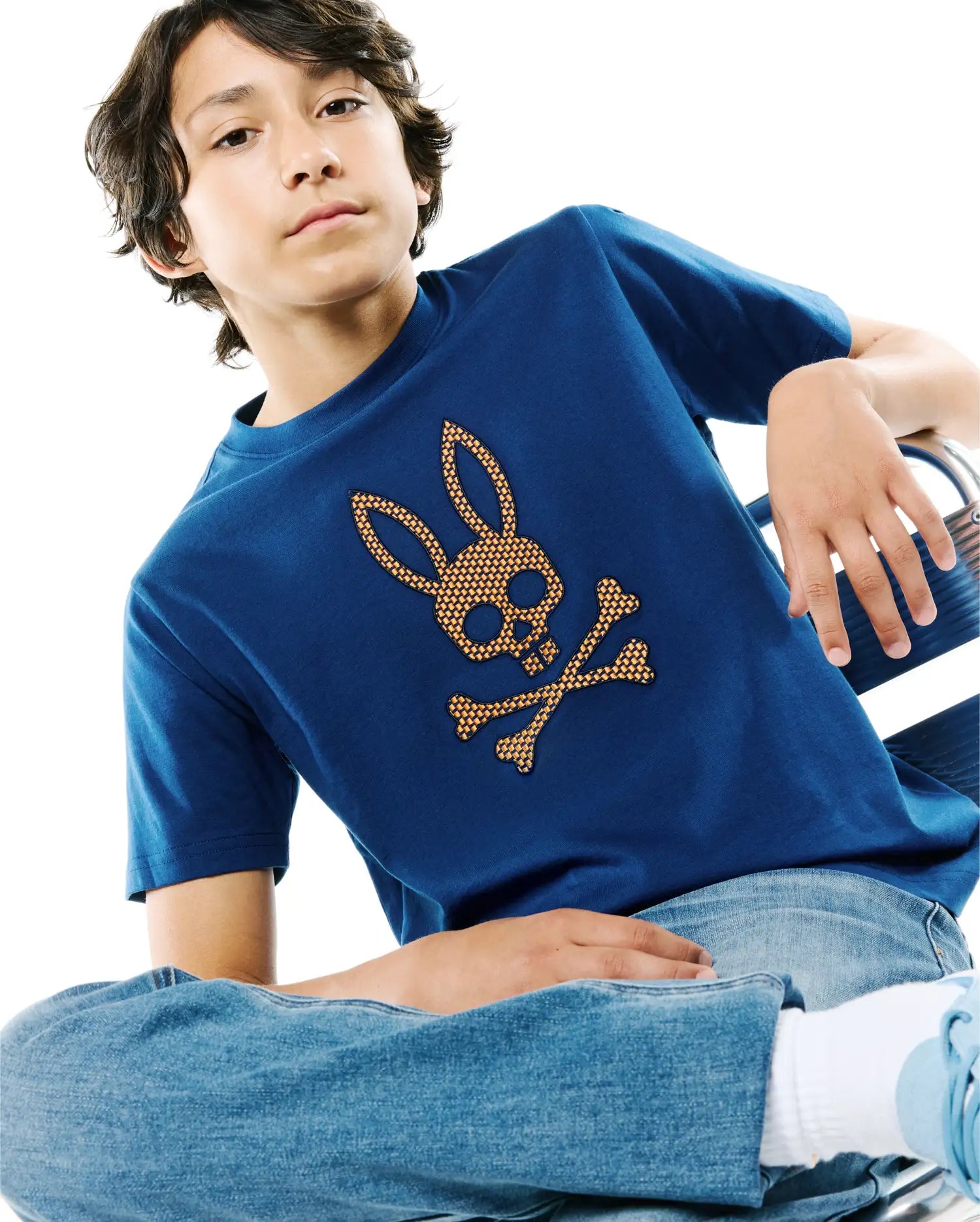 Kids Stan Graphic Tee in royal blue jersey knit, featuring a large central orange and gold woven Psycho Bunny skull and crossbones graphic, classic fit.