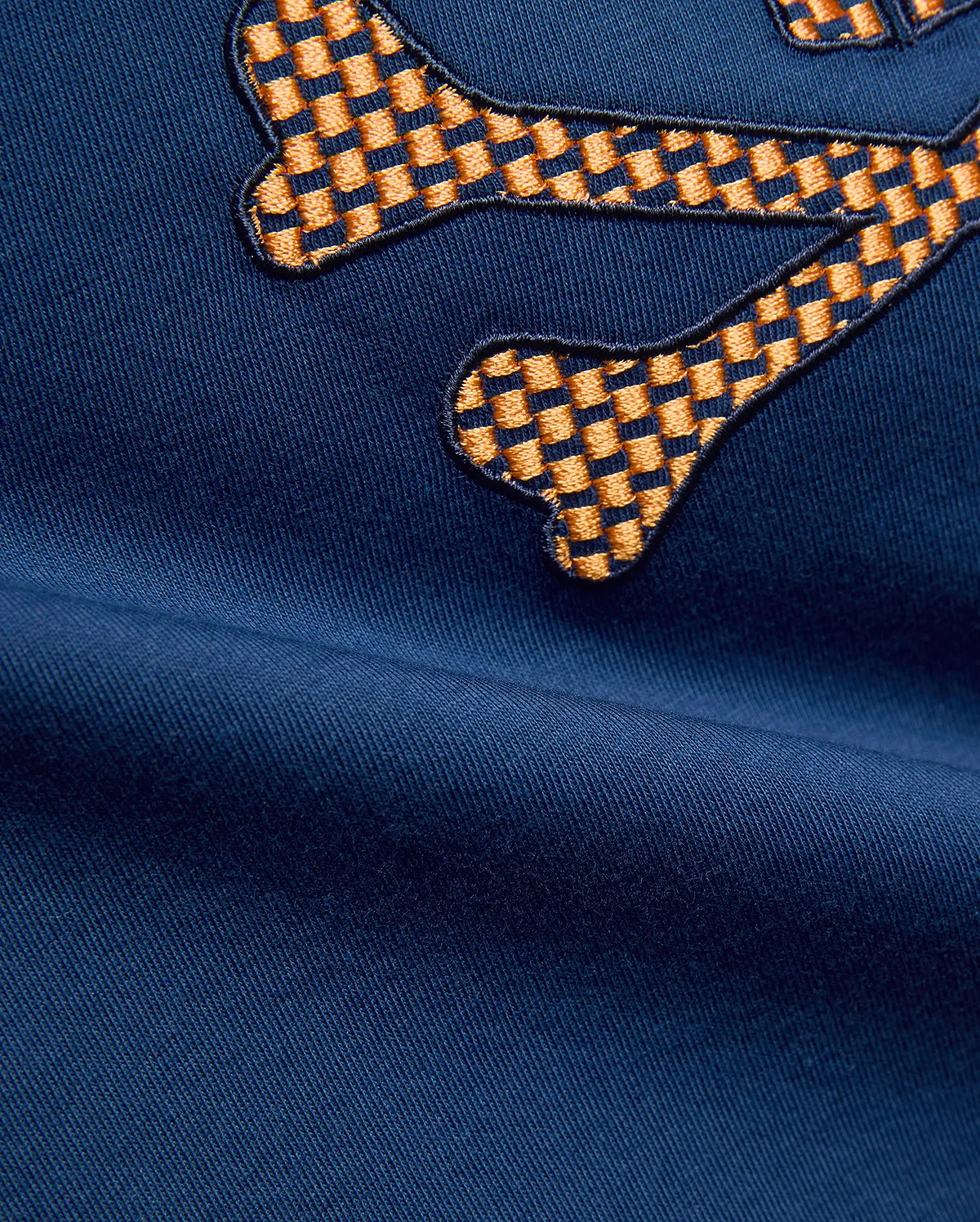 Kids Stan Graphic Tee in navy blue jersey fabric, featuring a large, prominent embroidered Psycho Bunny skull logo with an orange and dark blue checkered pattern.