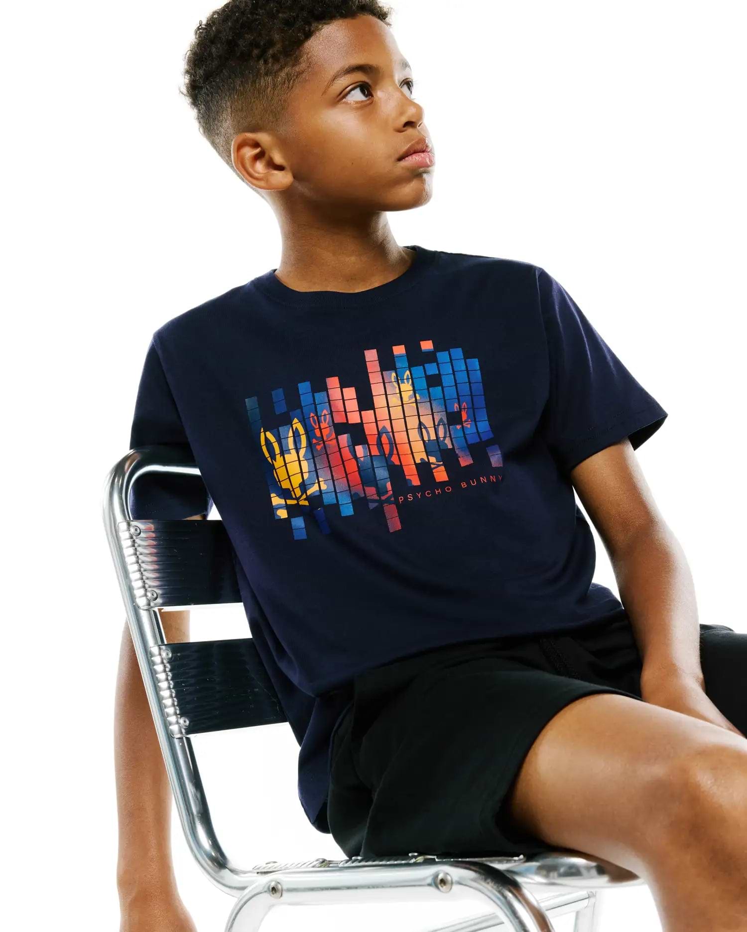 Kids Zander Graphic Tee, a navy classic-fit jersey t-shirt featuring a large pixelated Psycho Bunny skull logo graphic in orange, yellow, and blue on the chest, with Psycho Bunny text below.