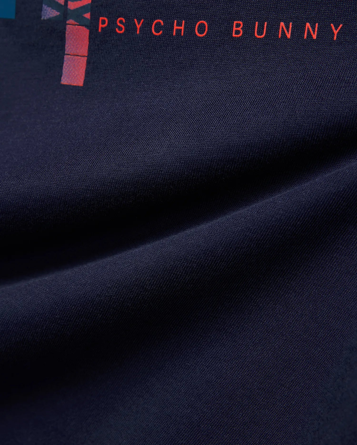 Kids Zander Graphic Tee, a navy jersey knit shirt with a vibrant red PSYCHO BUNNY text print and a modern abstract graphic design featuring red and purple hues.