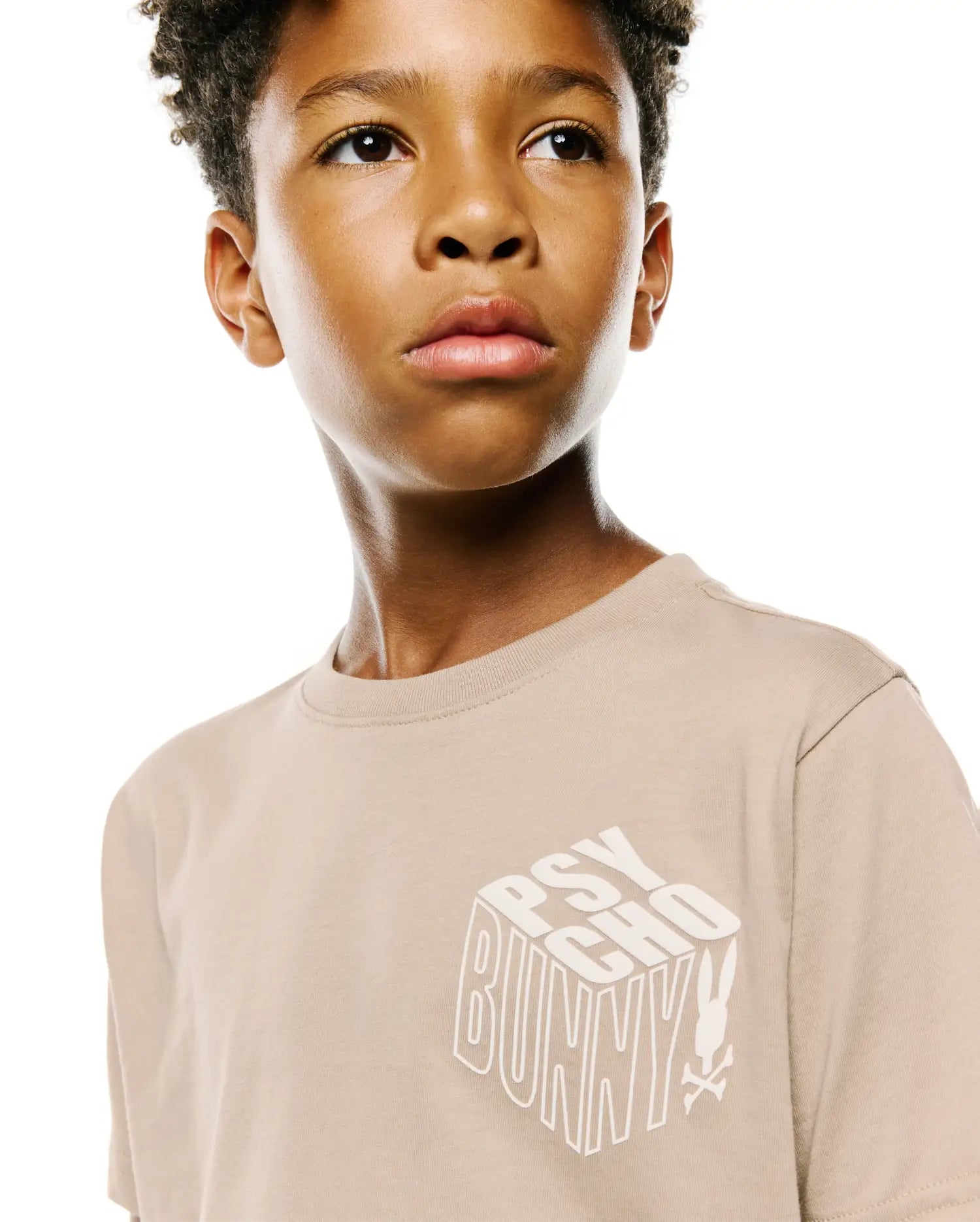 Kids Conan Back Graphic Tee in beige, featuring a classic fit and a large white 3D-effect PSYCHO BUNNY text graphic with the iconic bunny skull logo on the smooth jersey knit front.