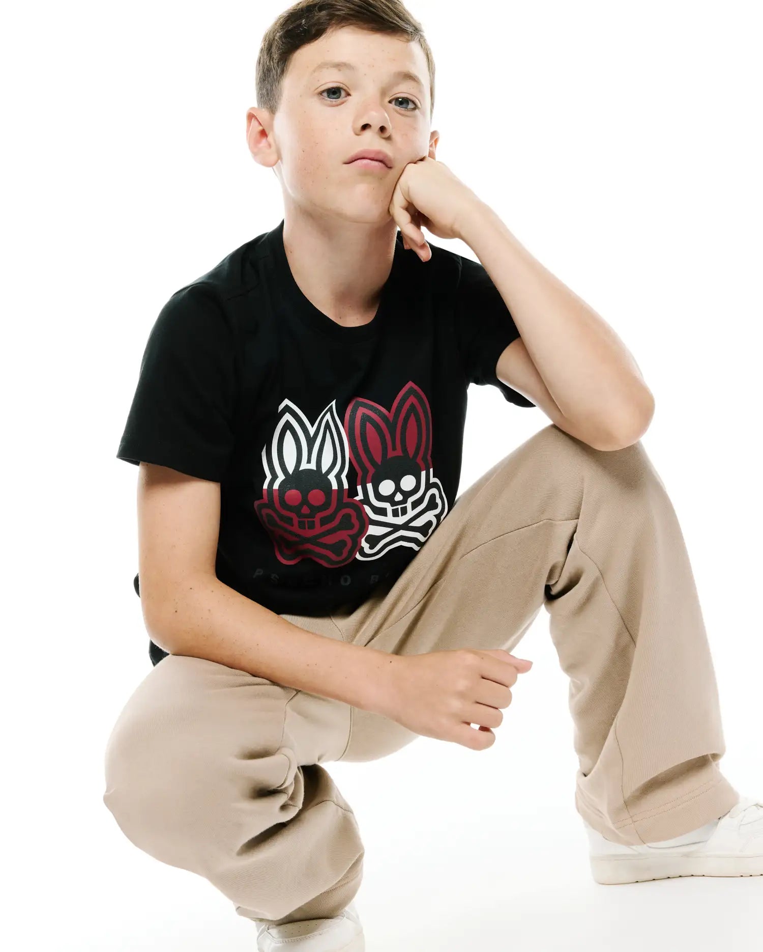 Kids Ledger Graphic Tee. Black classic fit jersey tee with a large central chest graphic featuring two Psycho Bunny skull logos, one red and one white, and Psycho Bunny text below.