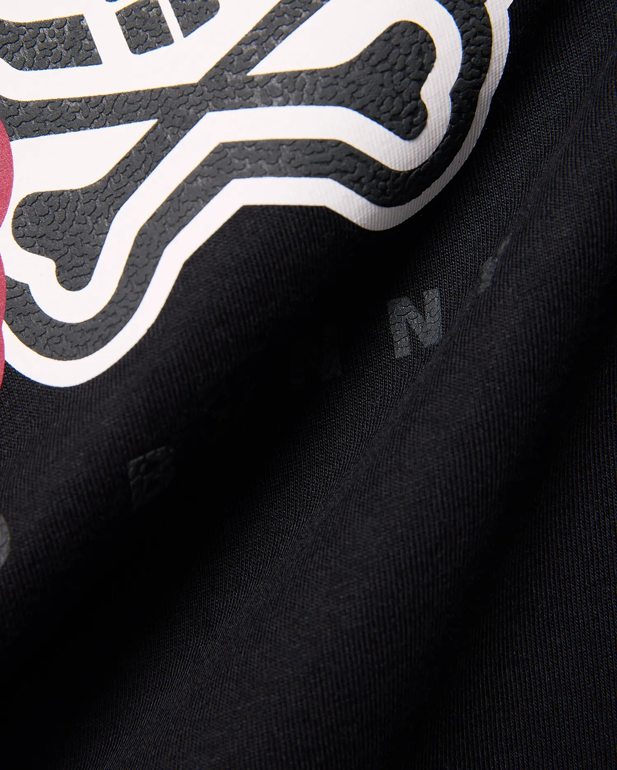 Kids Ledger Graphic Tee in black jersey knit, featuring a large, raised white and textured black Psycho Bunny skull graphic with a hint of dark pink, and subtle background letter prints.