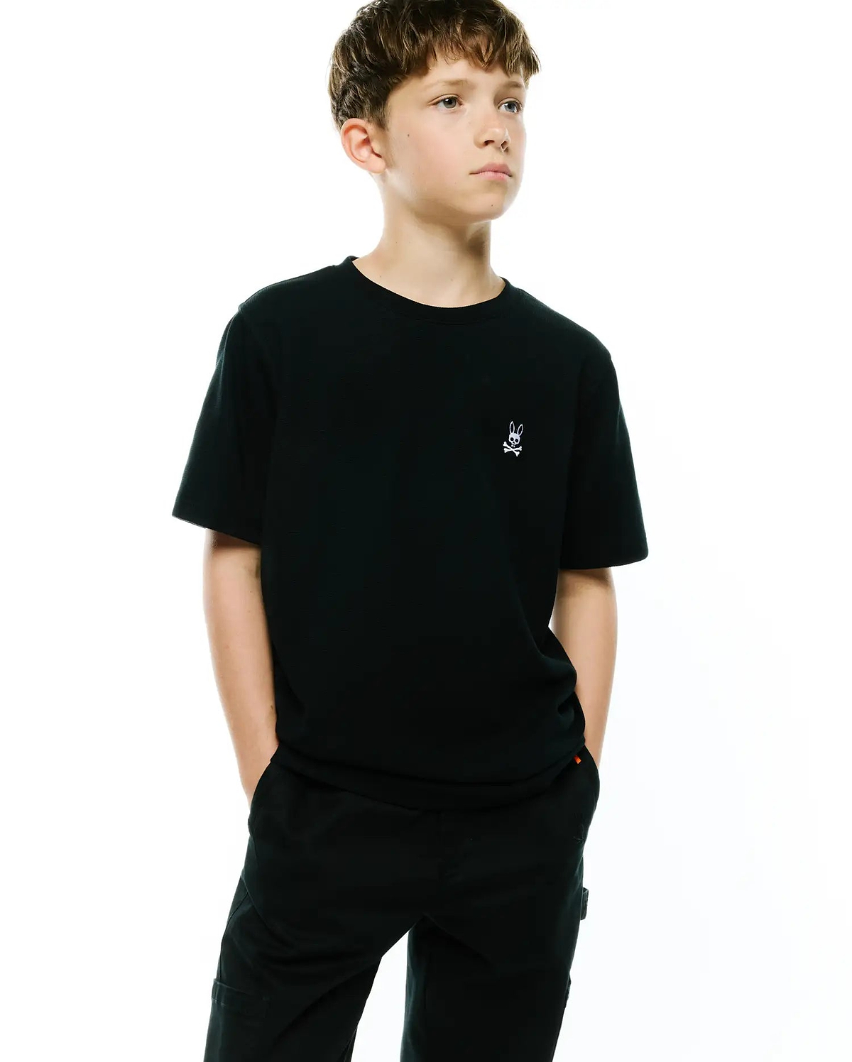 Kids Maxton Waffle Tee. Premium black classic fit waffle knit t-shirt featuring a small, crisp white embroidered Psycho Bunny skull and crossbones logo on the left chest, embodying refined streetwear style. (3)