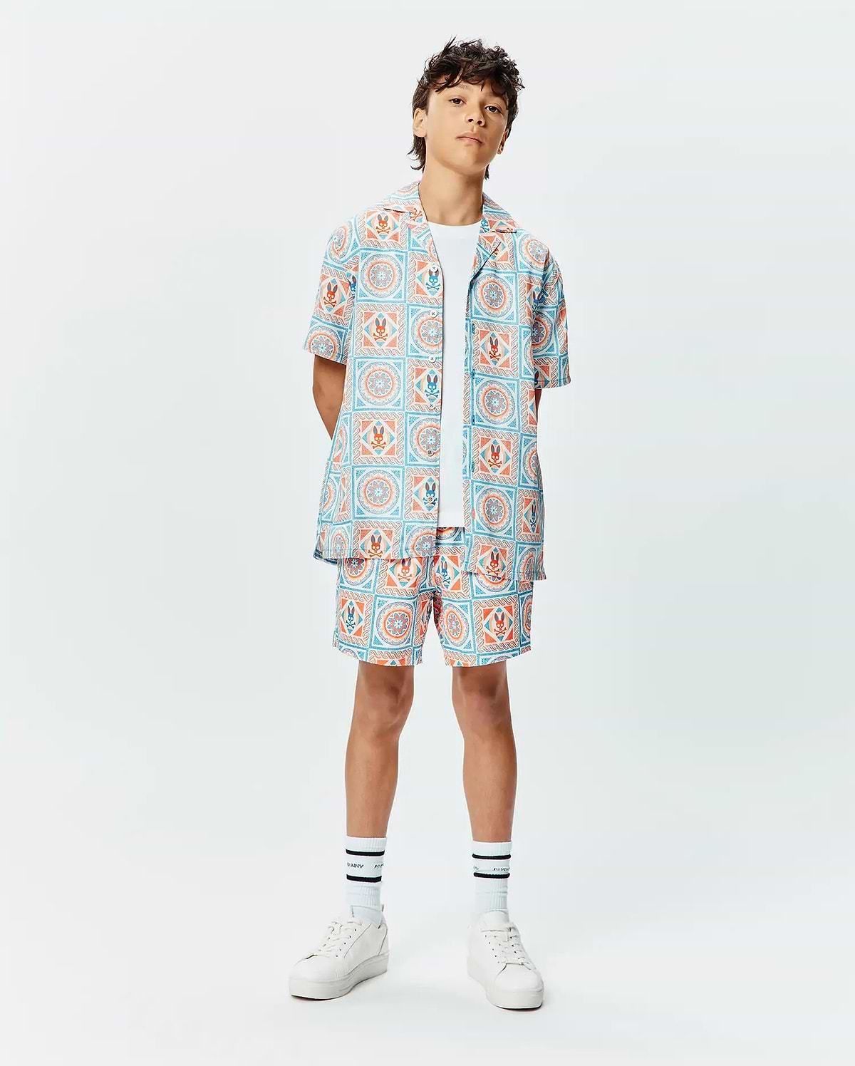 Kids Frank Tencel Shirt and matching relaxed-fit shorts, featuring a vibrant light blue and orange tiled geometric pattern with integrated Psycho Bunny skull logos throughout.