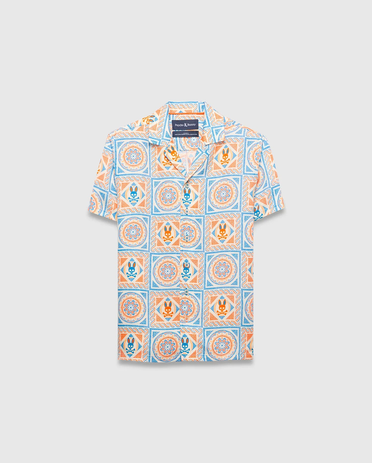 Kids Frank Tencel Shirt, a relaxed fit short-sleeve camp collar shirt in white Tencel, featuring an all-over light blue and orange tiled print with Psycho Bunny skull logos and floral patterns.