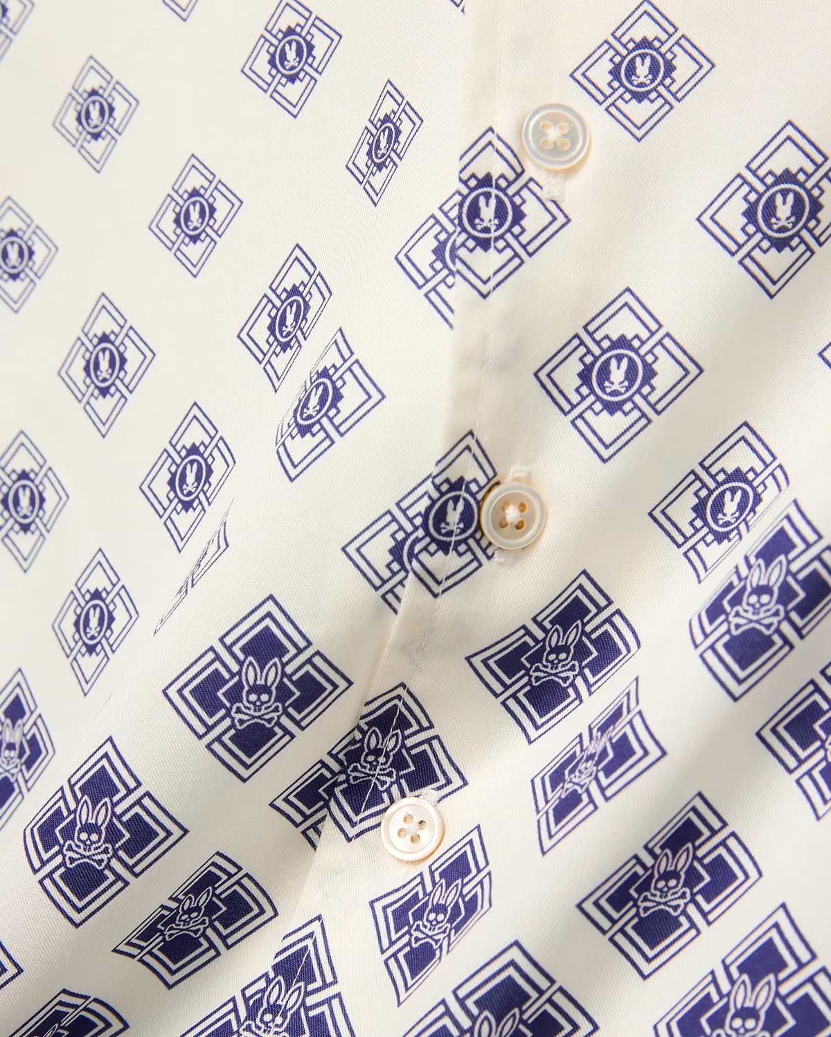 Kids Tobias Tencel Shirt in off-white with an all-over navy blue geometric pattern featuring the iconic Psycho Bunny skull logo, detailed with light brown buttons.